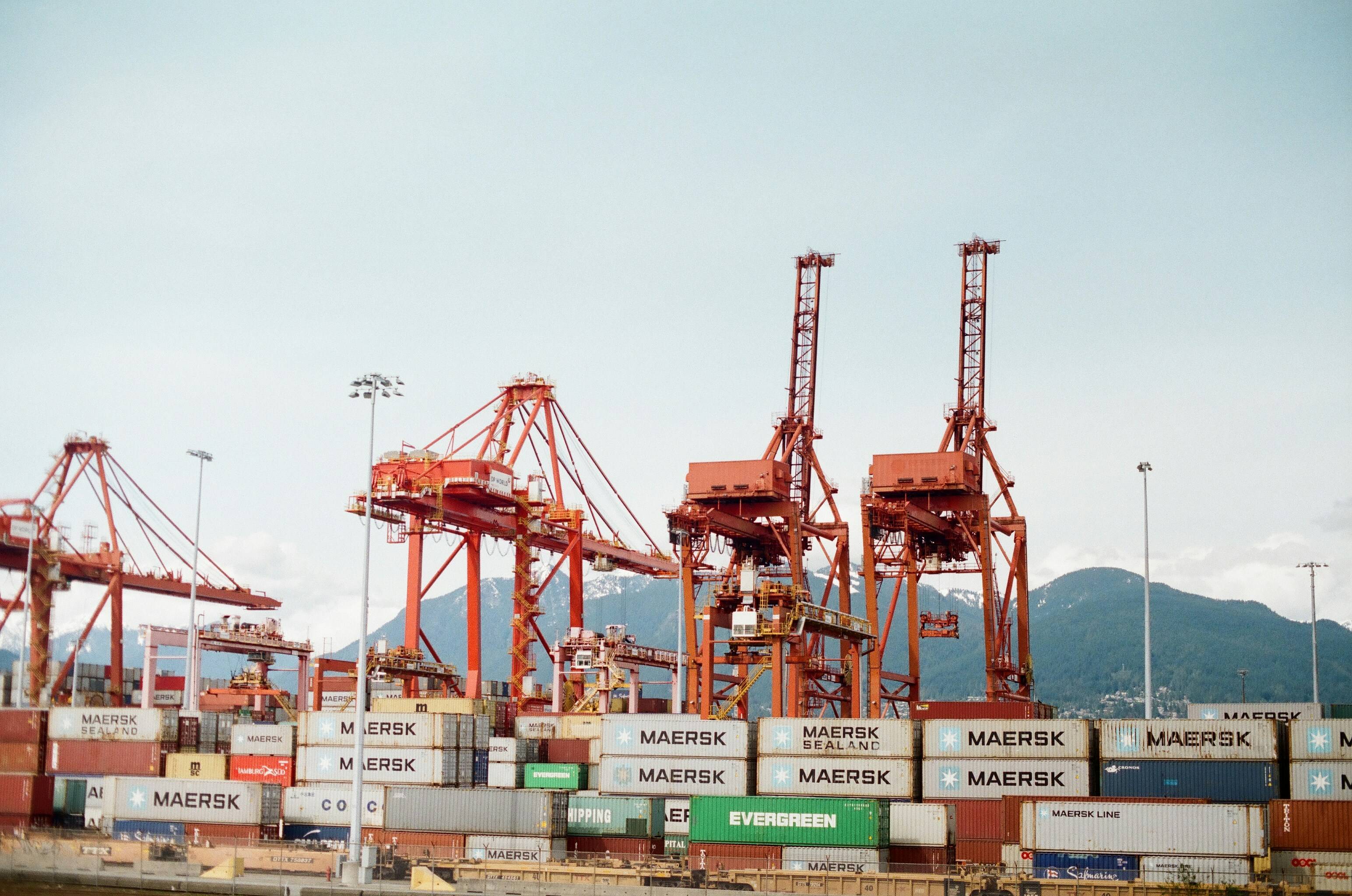 Port cranes with a mountain backdrop handling Maersk containers