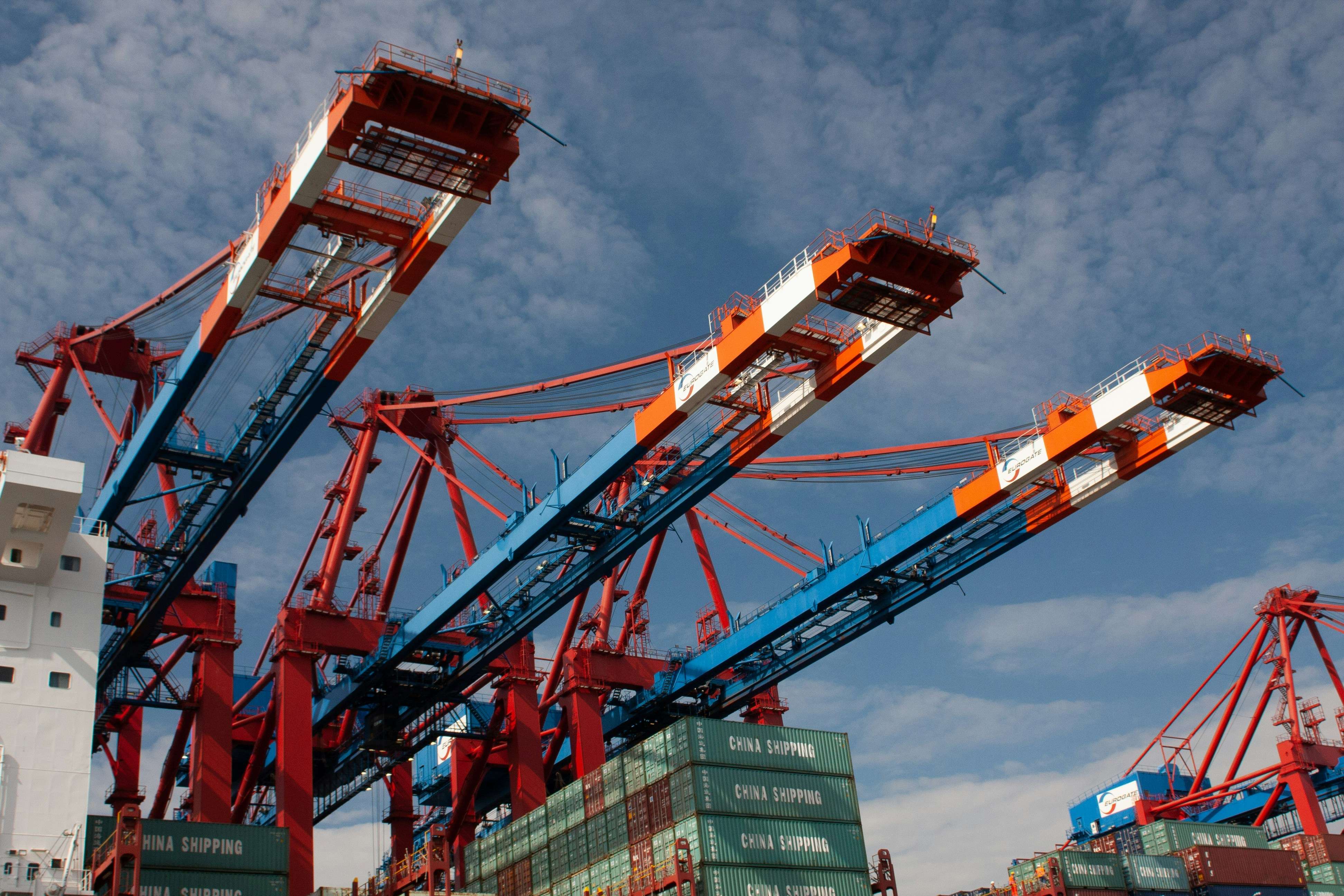 Ship-to-shore gantry crane booms handling shipping containers referenced in compliance guides