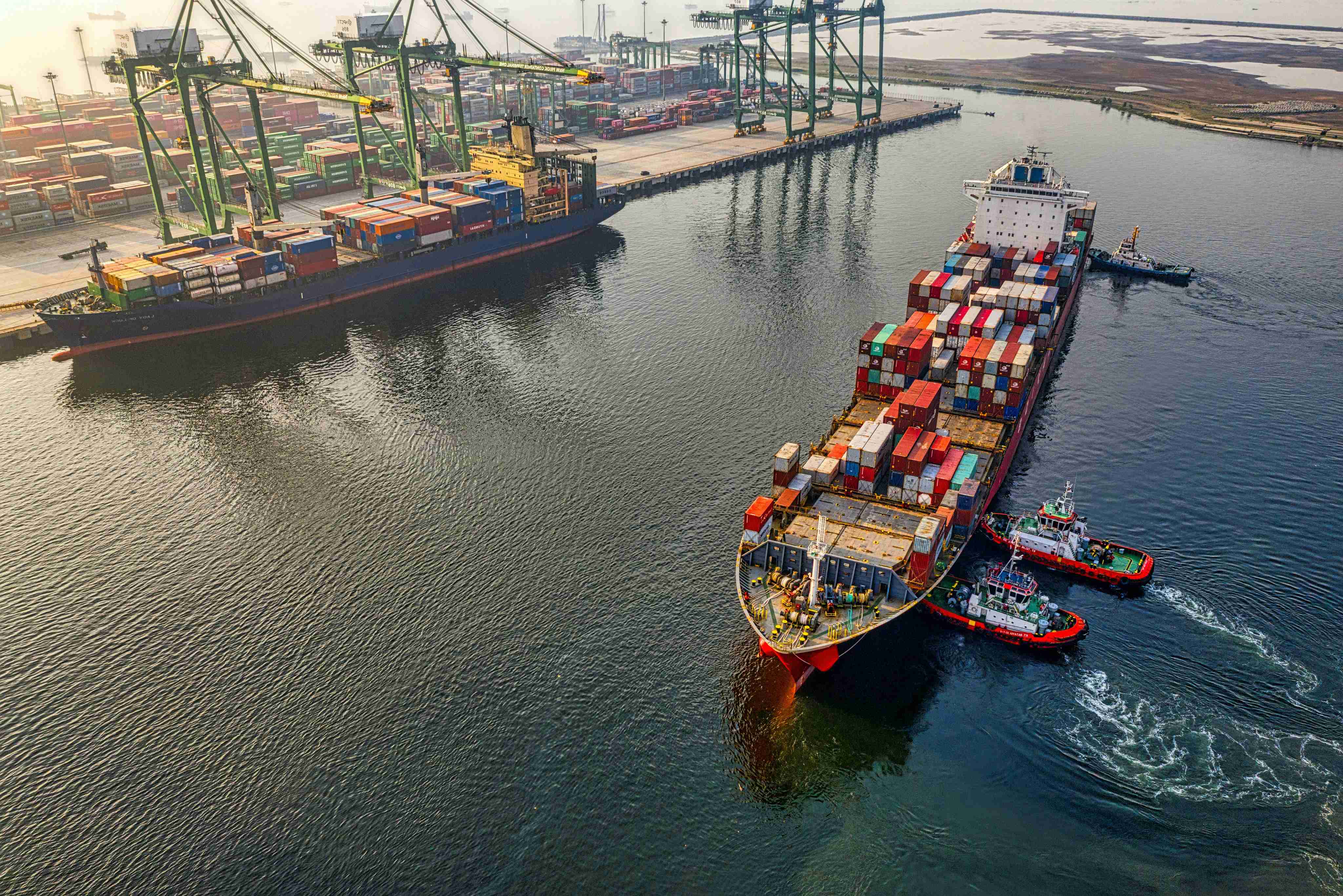 Tugboats guiding a vessel into the port channel, connecting inland industry to global trade